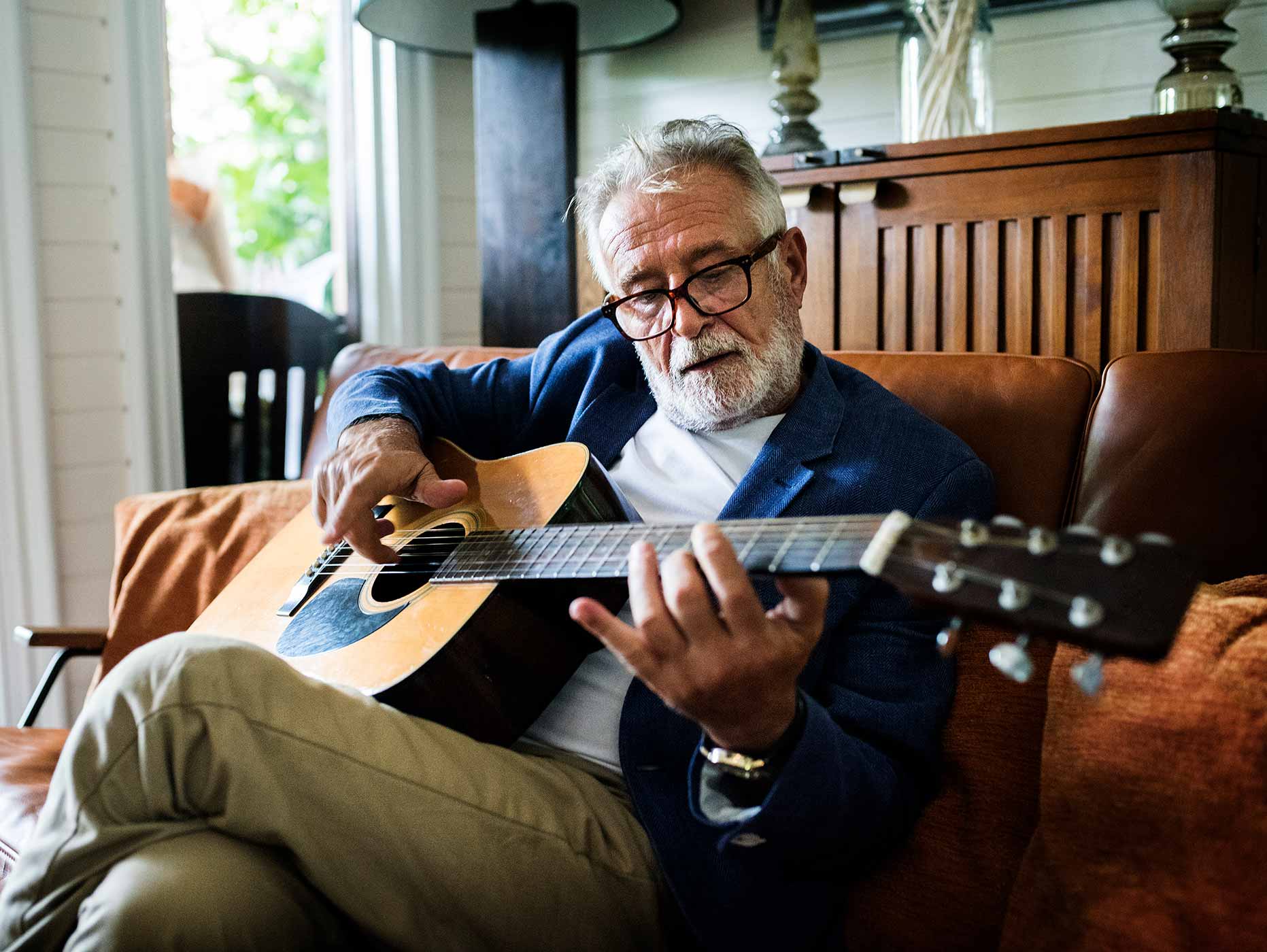 a senior man playing an acoustic guitar