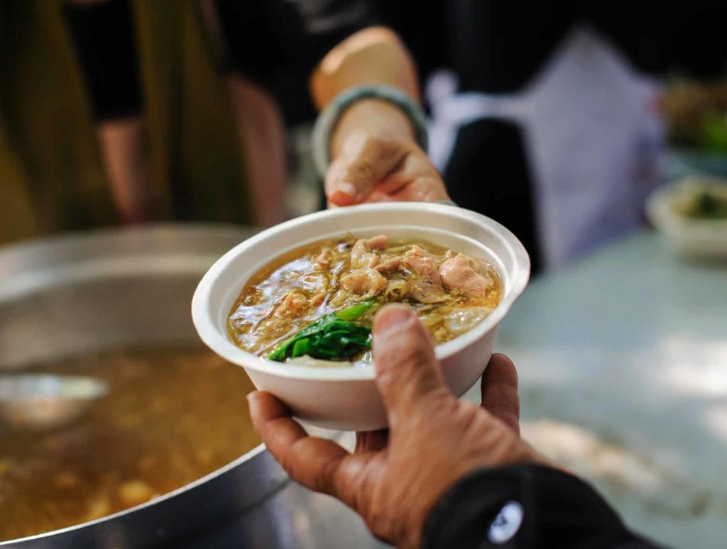 hands passing a bowl of soup