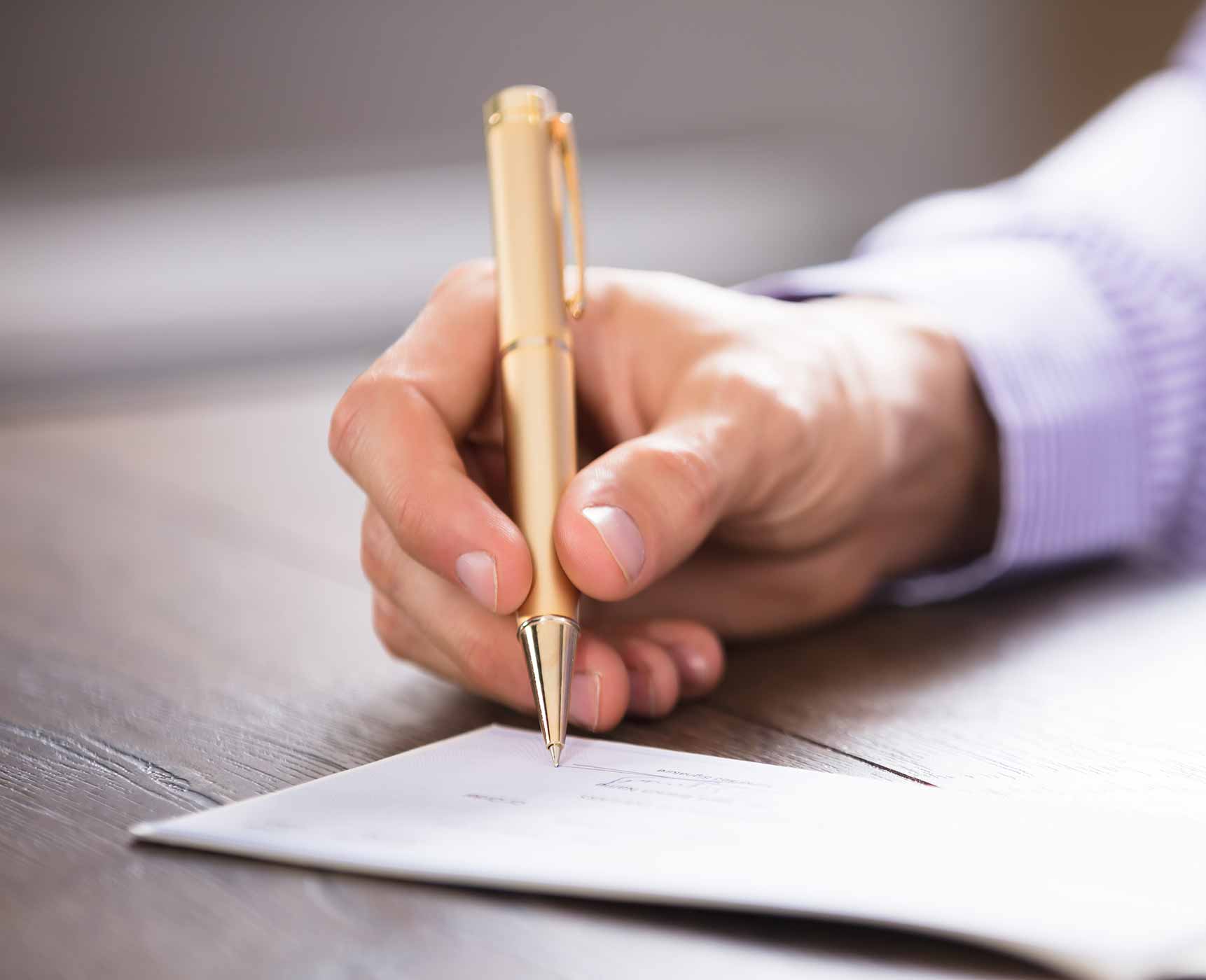 a male hand signing a check