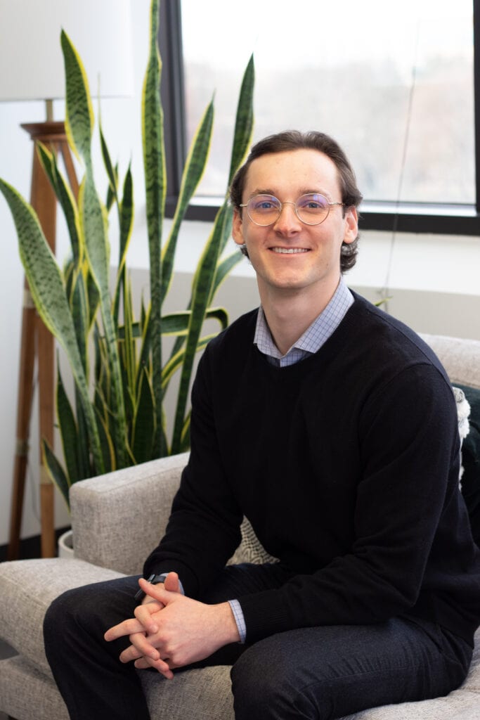 Luke Babner sitting in front of a tall plant